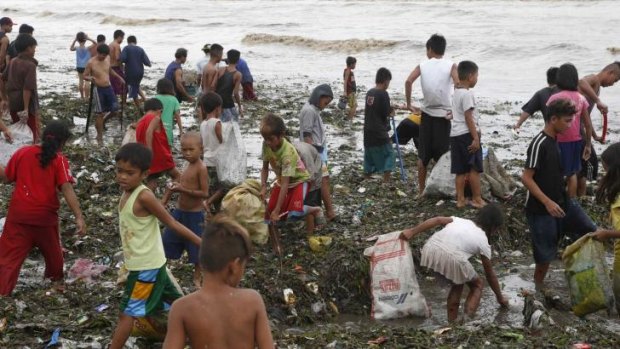 Residents gather salvageable items amidst debris after the onslaught of Typhoon Rammasun along the seashore of the coastal town of Rosario, Cavite southwest of Manila.