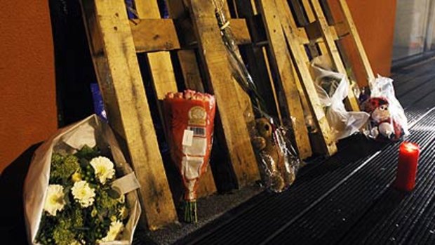 A candle and flowers, laid at the entrance of the creche where a man, his face painted white and with blackened eyes, stabbed to death two infants and a woman.
