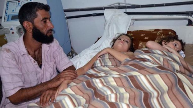 A man sits in a hospital near two children who activists say were affected by nerve gas in the Ghouta region, in the Duma neighbourhood of Damascus.