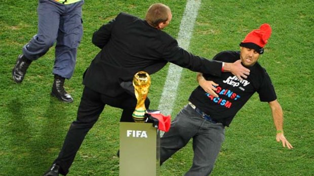 A security official tries to avoid a supporter from reaching the FIFA World Cup trophy.