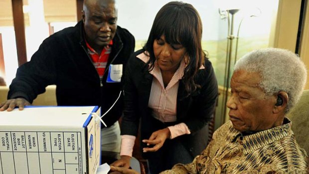 Nelson Mandela casts an early ballot at his home in Johannesburg,  assisted by his granddaughter Ndileka Mandela.