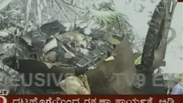In a photo made from television, an identified man uses a mobile phone near the wreckage of a plane in Mangalore, India.