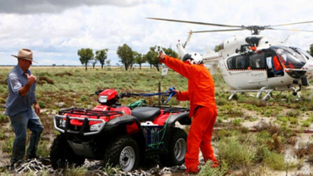‘‘A year’s rain in a couple of days’’ ... farmer Lance Carter, left, hopes to rescue stranded sheep with the quad bike the SES flew to his property near Brewarrina.