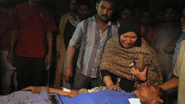 A woman weeps next to a family member injured in a bomb blast at a Sufi shrine, at a local hospital in Karachi, Pakistan.