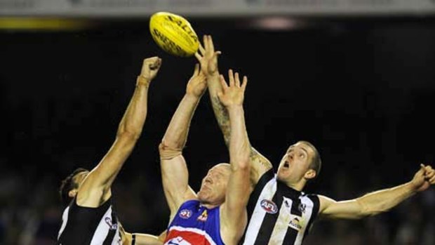 Collingwood's Dane Swan and Simon Prestigiacomo spoil Bulldog's Barry Hall in round one.