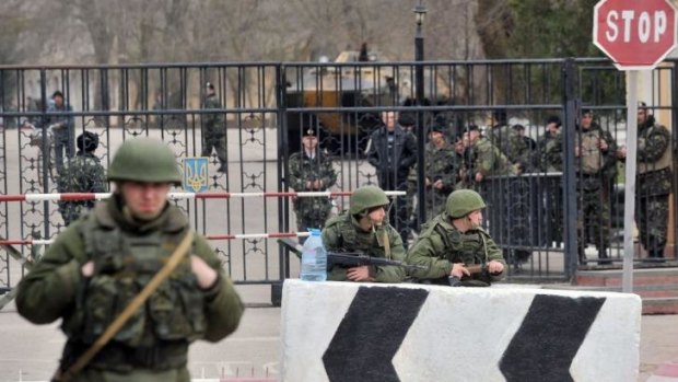 Uneasy neighbours: Members of the Russian armed forces (foreground) stand guard at the gate of a Ukrainian base in the small Crimean city of Kerch on March 4. Ukrainian troops can be seen behind the gate.