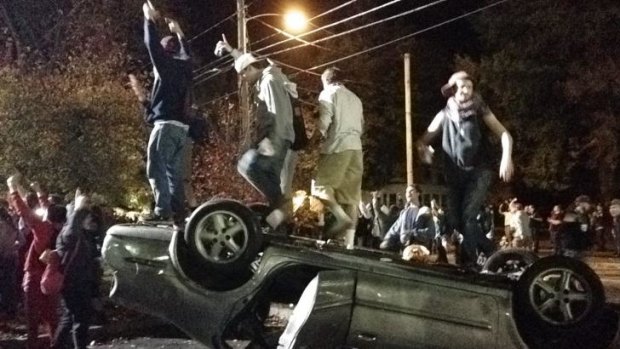 Wild ... People stand atop an overturned car in Keene, New Hampshire during a night of violent parties that led to dozens of arrests and multiple injuries, near the city's annual pumpkin festival. 