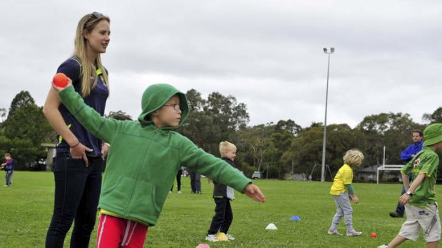 Ellyse Perry gives some bowling tips to Lucas Sanden, 5, in Canberra on Saturday.