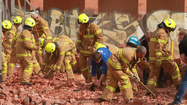 Firemen and workers with bare hands frantically dig into the fallen brick wall in Swanston Street in 2013.