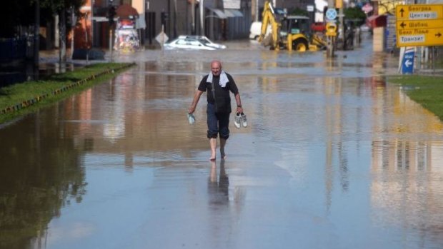 A man holds his shoes as he walks barefoot in a street in the Serbian town of Obrenovac, some 30km southwest of Belgrade, flooded by the river Sava.