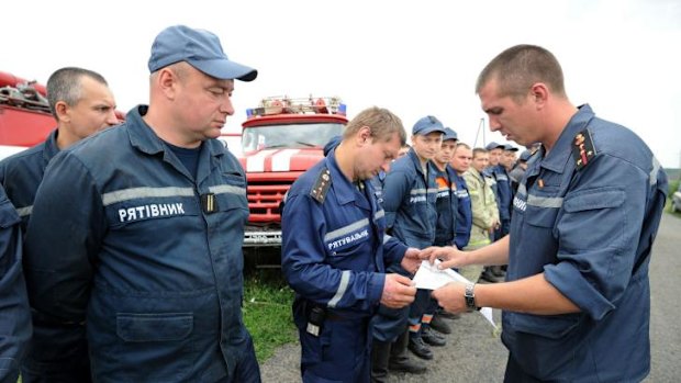 Emergency workers receive instructions from a firefighter before searching bodies on the site of the crash of a Malaysian airliner carrying 298 people, near the town of Shaktarsk, in rebel-held east Ukraine.