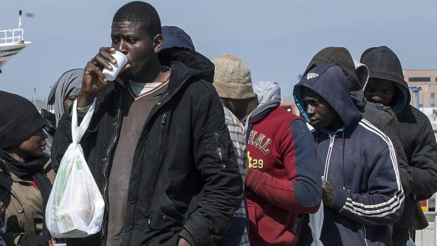 Rescued migrants line up after disembarking at the southern Italian port of Corigliano, Italy.