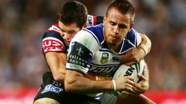 Josh Reynolds of the Bulldogs is tackled by Daniel Mortimer of the Roosters.
