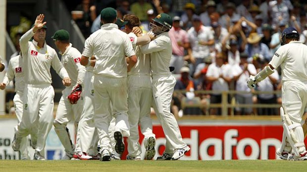 On his way: Australian players celebrate after Ryan Harris took the wicket of Sachin Tendulkar on the opening day of the third Test in Perth yesterday.