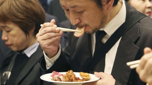 A man eats a slice of whale meat during the 26th whale meat tasting event in Tokyo on Tuesday, April 15, 2014.