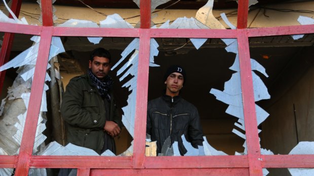 An Afghan shopkeeper watches from the broken window of his shop near the site of suicide car bomb attack in Kabul, Afghanistan, last month. 