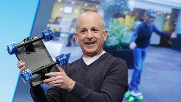 Steven Sinofsky, President of Windows and the Windows Live Division at Microsoft, holds up a Surface tablet with skateboard wheels attached.