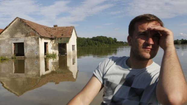 A Bosnian man in a boat searches for people and animals after flooding in the village of Vojskova near the Bosnian town of Bosanski Samac.