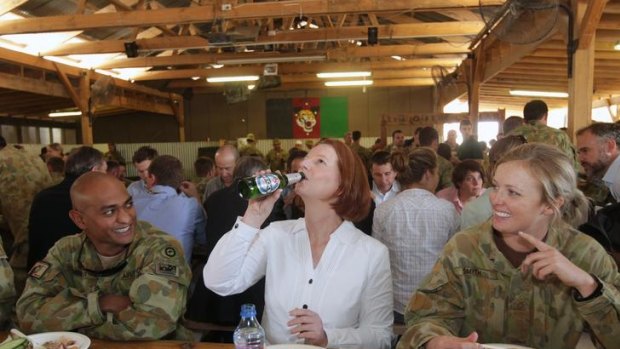 Prime Minister Julia Gillard drinks a Beck's Non-Alcoholic beer offered to her by Sergeant Vernon Pather (left) as Private Emily Smyth (right) looks on, during a BBQ lunch at the Multi-National Base in Tarin Kowt, Afghanistan.