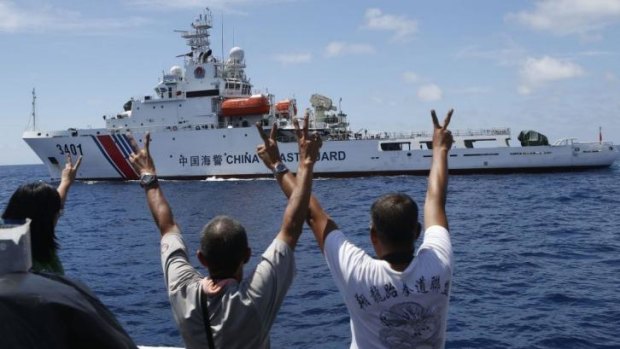 Philippine Marines and a local television reporter (left) gesture towards a Chinese Coast Guard vessel, which twice attempted to block a Philippine government supply ship from reaching the disputed Second Thomas Shoal.