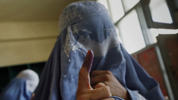 An Afghan woman shows her inked finger after casting her vote, during the presidential election day at a polling station in Kandahar province south of Kabul, Afghanistan.