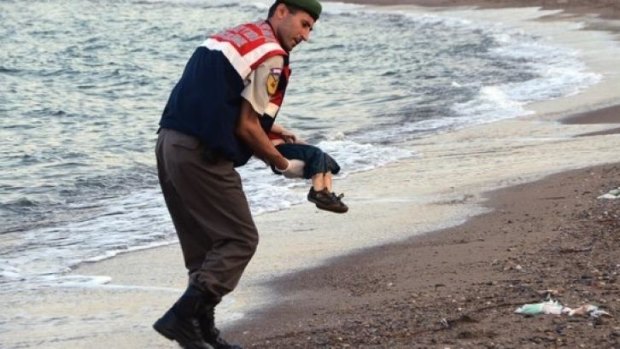 A police officer carries Aylan Kurdi after he washed up on a beach near the Turkish resort of Bodrum.