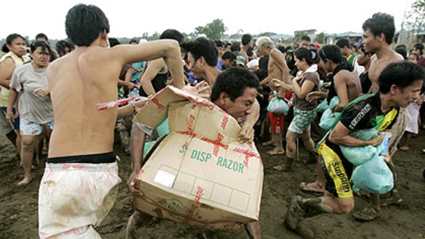 A man holds on tightly to a box of relief goods as a crowd scrambles for aid delivered by military helicopter in Rodriquez, Rizal province.