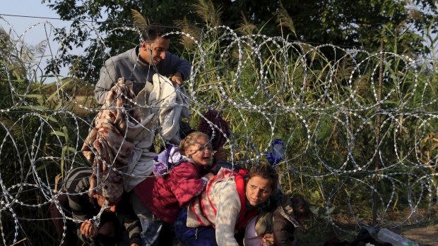 Syrian migrants wriggle under razor wire to get into Hungary on Thursday. 