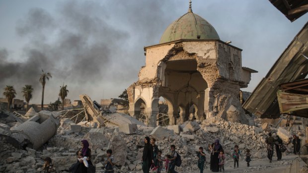 Fleeing Iraqi civilians walk past the heavily damaged al-Nuri mosque in the Old City of Mosul.
