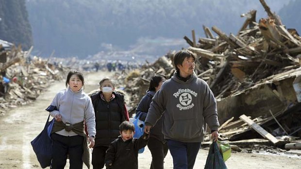 Long road . . . victims walk through the obliterated town of Minami Sanriku.