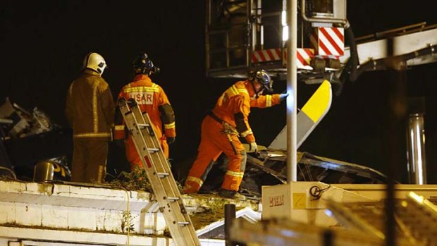 Rescue workers examine the wreckage of a police helicopter which crashed onto the roof of the Clutha Vaults pub.
