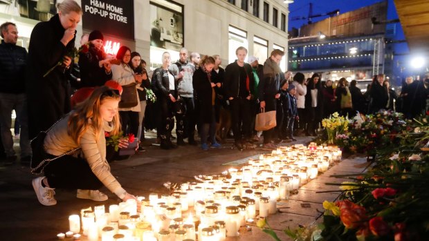 A woman places a candle in front of the department store Ahlens in Stockholm on  Sunday.