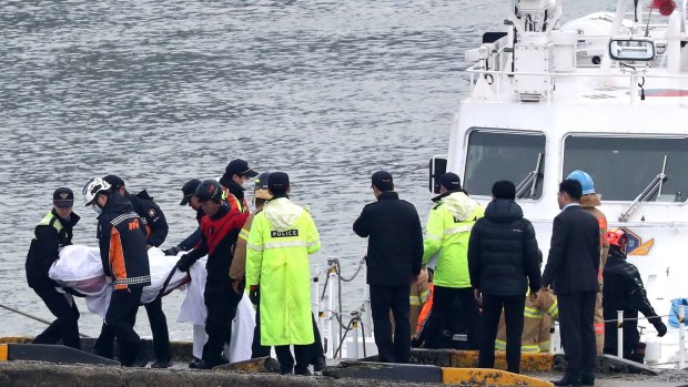 South Korean police officers and rescue workers carry a victim of a boat capsizing at a port in Incheon, South Korea.