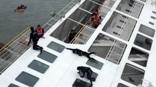 Maritime officers, in black, rescue passengers from the sinking ferry.