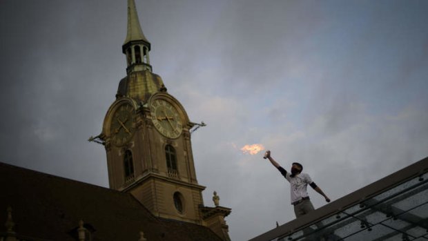 Rooftop protest: A man ignites a spray can in the centre of Berne as the Swiss capital was locked down for the techno parade.
