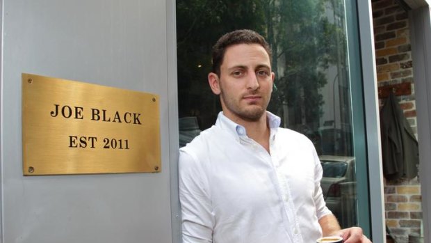 Battling ... Ben Sweeten owner of Joe Black cafe, Surry Hills, next to his sign.