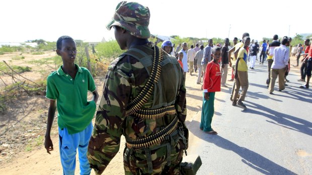A Kenya Defense Force soldier stops a boy from moving in the direction where Islamists are holding hostages on a campus in Garissa.
