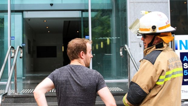 Ben Harrison speaks to a firefighter after a fire alarm and building evacuation on Turbot Street, Brisbane.