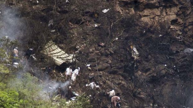 Wreckage ... rescue workers look for survivors at the site of the crash in the densely wooded Margalla Hills yesterday. At least 150 people were on board the plane.