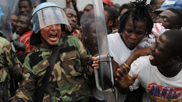 A Peruvian peacekeeper tries to control a crowd during food distribution in Port-au-Prince.