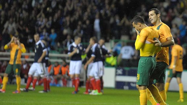 Losing streak ... Sasa Ognenovski of Australia consoles Jason Davidson after his own goal condemned the Socceroos to defeat against Scotland.