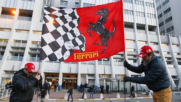 Fans plant a Ferrari flag in the ground in front of the emergency unit of the hospital in Grenoble where Michael Schumacher is being treated.