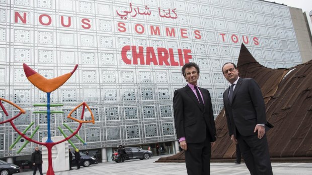 French President Francois Hollande (right) and the President of the Institut du Monde Arabe (Arab Institute), Jack Lang pose in front of the Arab Institute building bearing the message 'We are Charlie', in Paris.