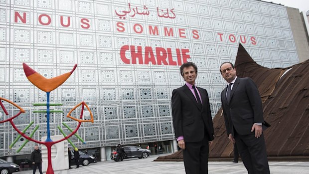 French President Francois Hollande (right) and the President of the Institut du Monde Arabe (Arab Institute), Jack Lang pose in front of the Arab Institute building bearing the message 'We are Charlie', in Paris.