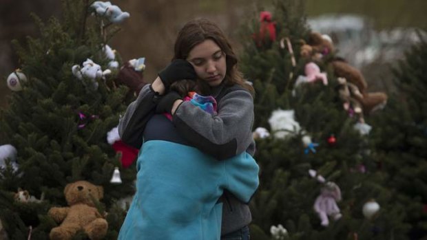Siblings hug in front of a row of Christmas trees, which line the street near Sandy Hook Elementary School.
