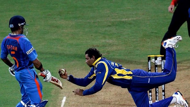 Tillakaratne Dilshan of Sri Lanka dives to take a catch off his own bowling to dismiss Virat Kohli of India.