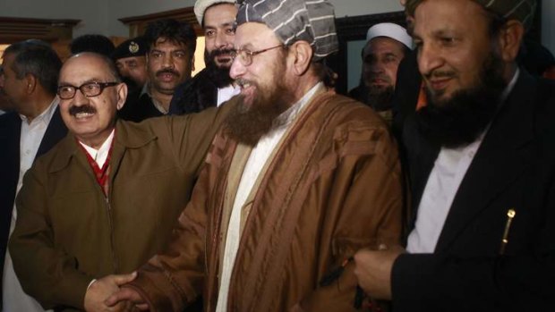 Maulana Sami ul-Haq (centre), one of the Taliban negotiators, and Irfan Siddiqui (left), a Pakistan negotiator, shake hands.
