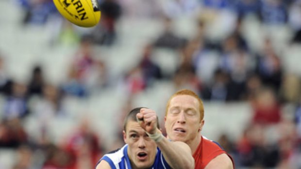 Kangaroos forward Leigh Harding handballs during a match against Melbourne, with Demons forward Matthew Bate defening.