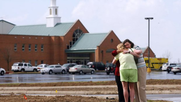 Mourners comfort each other in front of the First Baptist Church in Maryville, Illinois, where a gunman shot dead the pastor and injured several others.