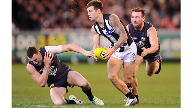 That's got to hurt: Carlton's Mitch Robinson clutches his shoulder as Magpie Jamie Elliott heads upfield.